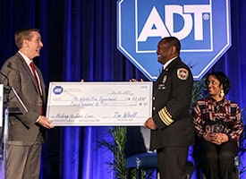 ADT CEO Tim Whall presents a check to Ft. Worth Fire Department Fire Chief Rudy Jackson