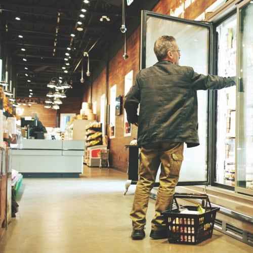 Man reaching into grocery store freezer
