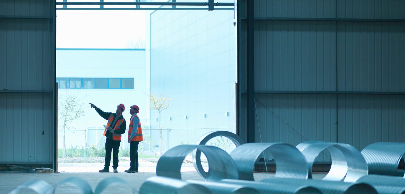 Two people in hard hats surveying a warehouse