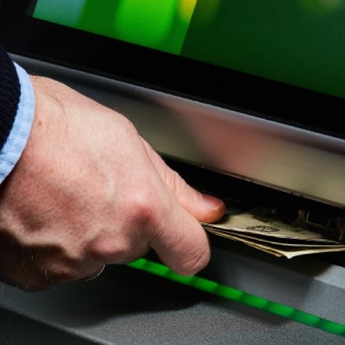 Hand withdrawing cash from an ATM